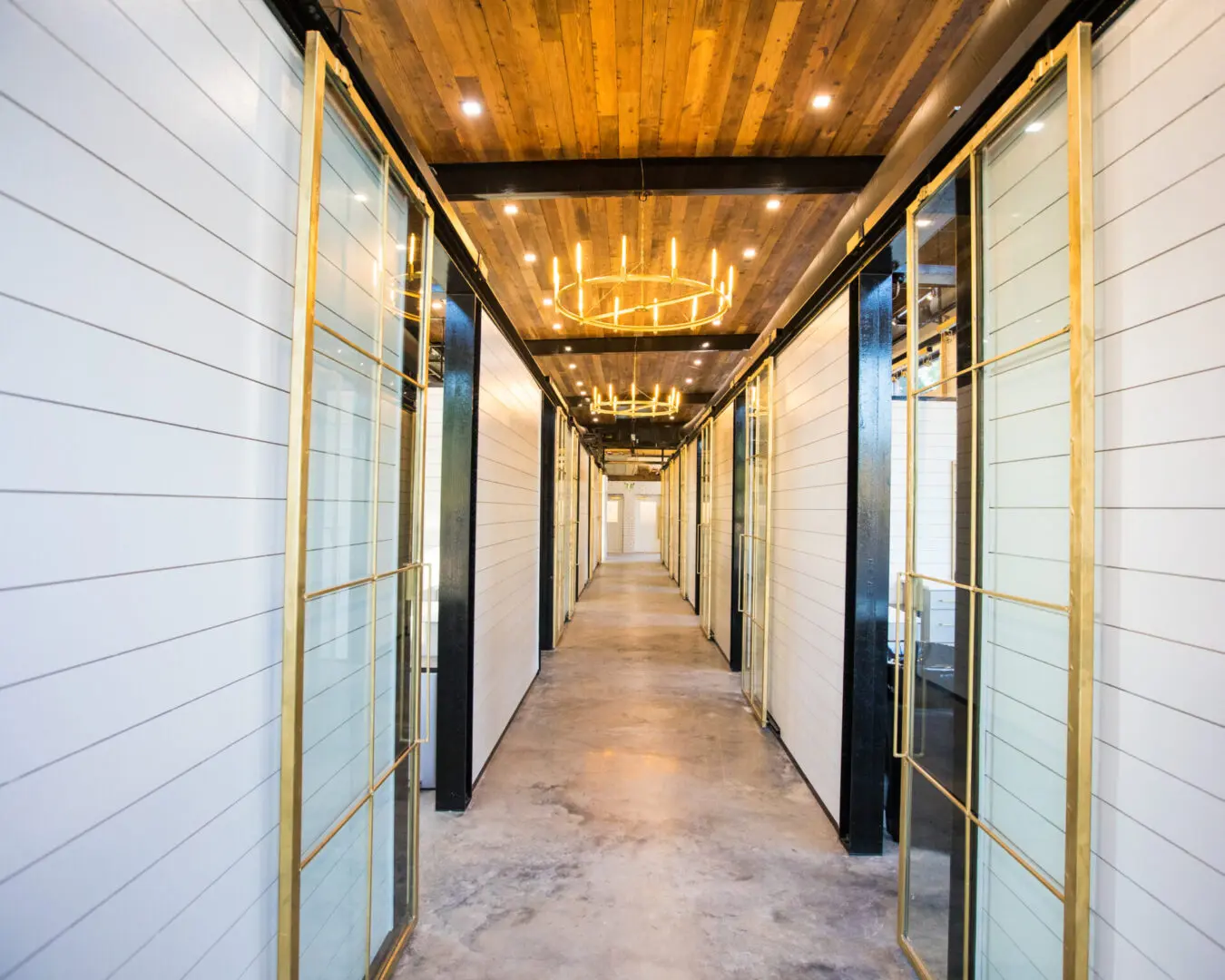 A hallway with a candle chandelier and white walls.