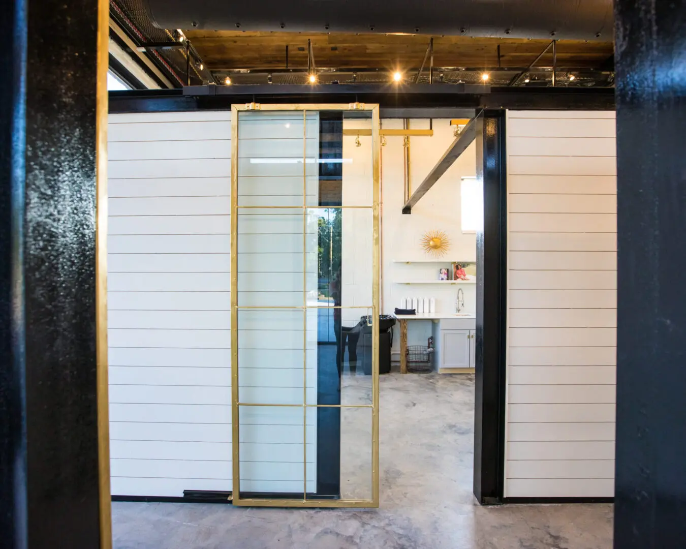 A black and white office with a glass door and lights around